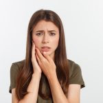 Donna con dolore dentale: come curare la parodontite e alleviare il fastidio.