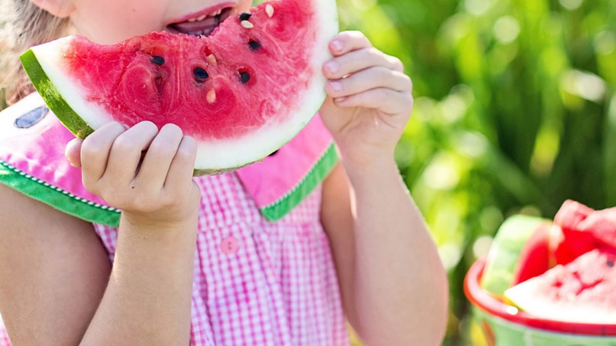 Bambina gusta anguria: alimentazione sana per lo sviluppo orale. Frutta e crescita armonica, dieta infantile.