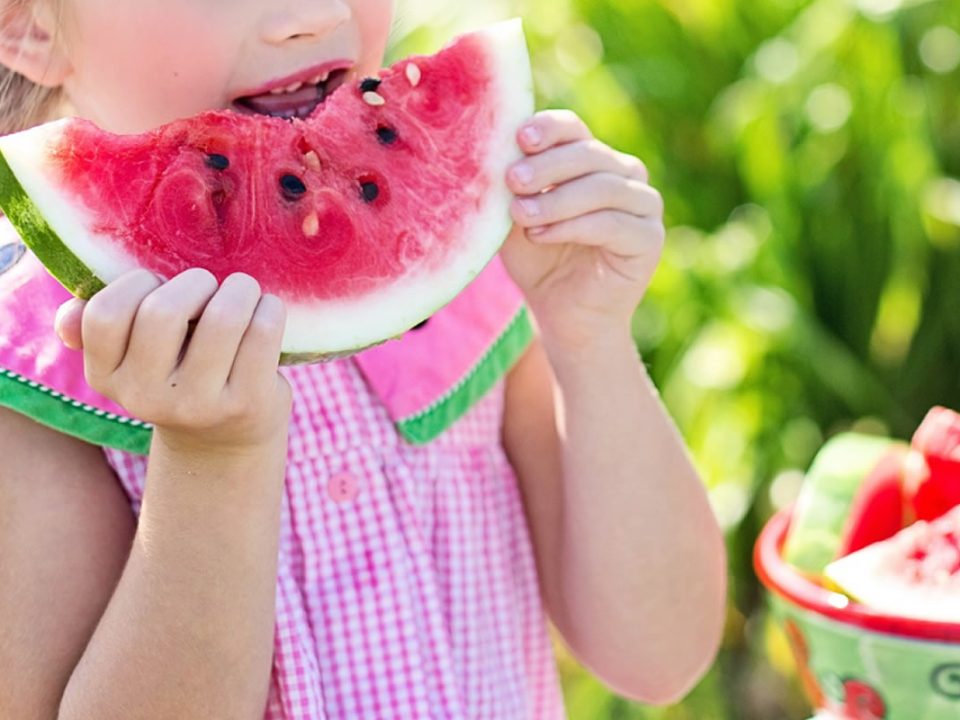 Bambina gusta anguria: alimentazione sana per lo sviluppo orale. Frutta e crescita armonica, dieta infantile.
