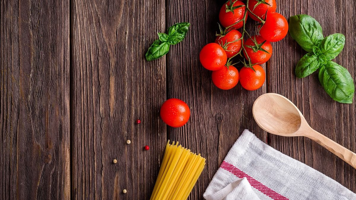 Alimentazione e igiene orale: pomodori, basilico e pasta su legno. Ispirazione per la cura dentale con cibi sani.