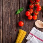 Alimentazione e igiene orale: pomodori, basilico e pasta su legno. Ispirazione per la cura dentale con cibi sani.