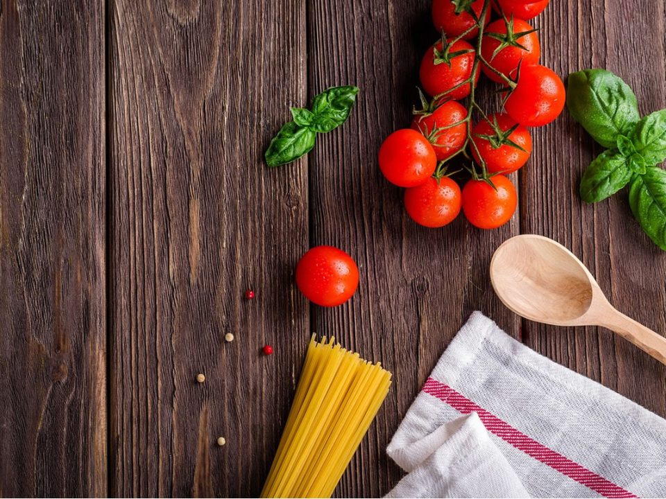 Alimentazione e igiene orale: pomodori, basilico e pasta su legno. Ispirazione per la cura dentale con cibi sani.