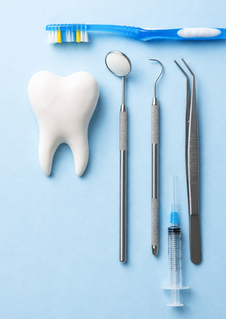 Igiene orale Piacenza e Lodi: spazzolino, specchietto, dente, pinze e siringa per la prevenzione dentale.